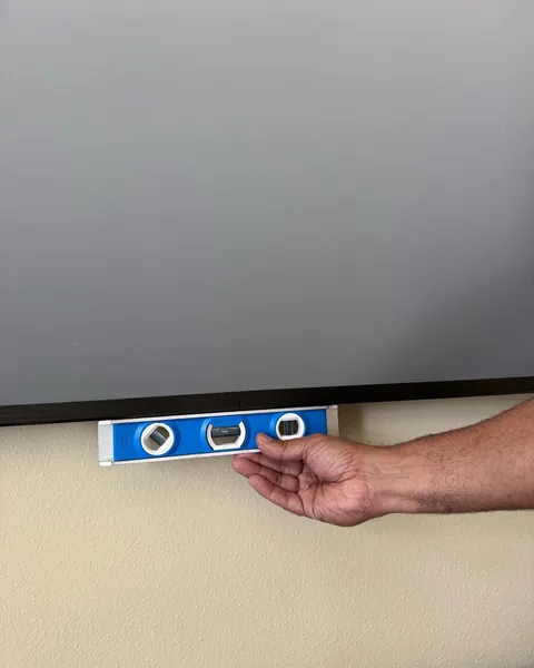 Technician leveling a large projector screen installation